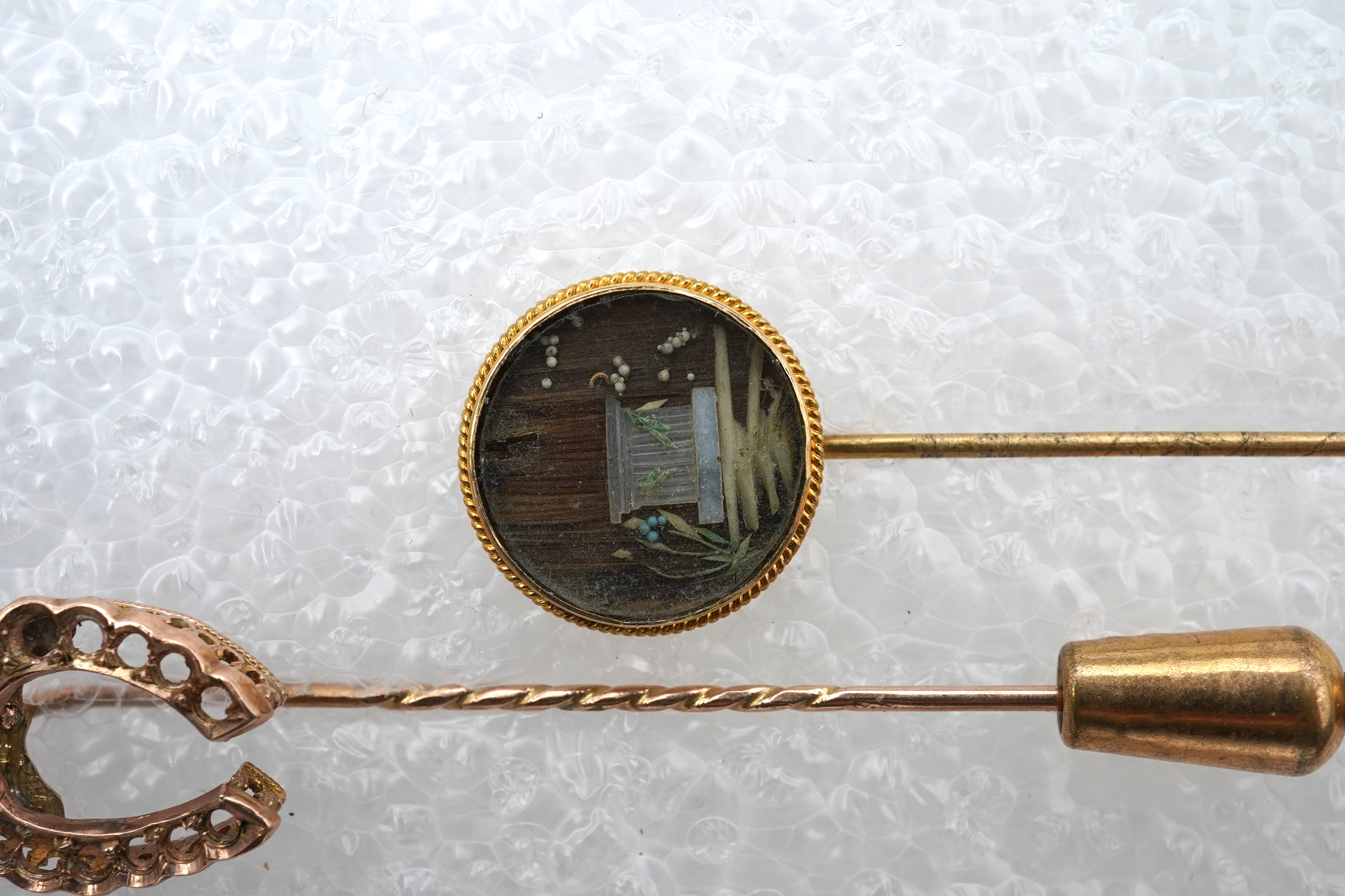 Two stick pins and a jadeite bar brooch, comprising: a bar brooch centring on an insect set with a pear-shape jadeite cabochon and a pearl, mounted in gold, length 7.5cm, stamped 14K, base metal pin; a stick pin capped w